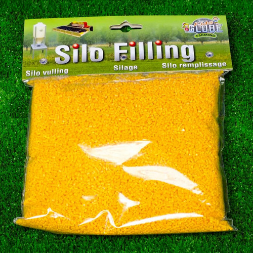 A package of yellow "Silo Filling" model landscape material on green grass. The label includes images of miniature models and text in three languages.
