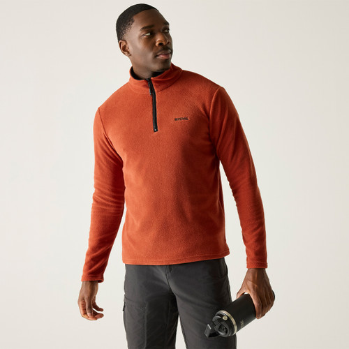 A front view of a man wearing an orange Regatta half zip fleece on a white background