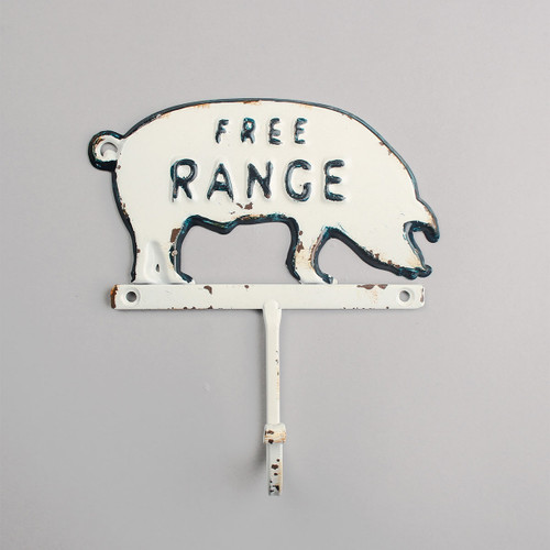 A vintage-style metal pig sign reading "Free Range," with weathered white paint and blue accents, evokes a rustic, farmhouse feel.