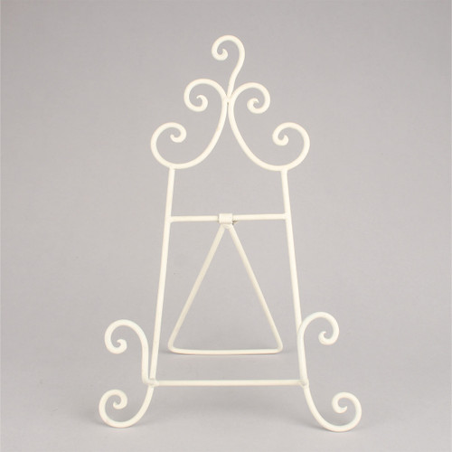Ornate white metal easel with swirling designs on top and bottom against a plain grey background. Elegant and decorative appearance.