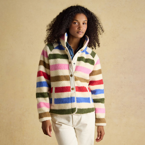 Women’s multicoloured striped sherpa fleece jacket with high collar, snap-button fastening and cream trim, worn with light trousers.