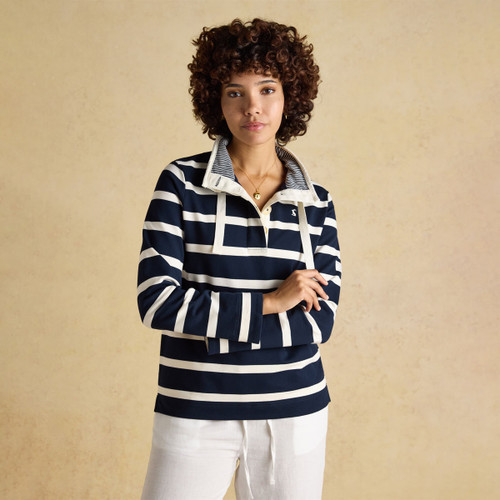 Navy and white striped women’s sweatshirt with a high buttoned collar and drawcords, worn by a model with white trousers.