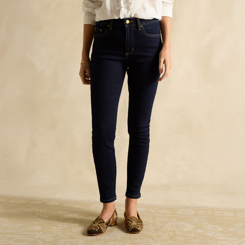 Woman wearing dark-wash high-waisted skinny jeans paired with a white blouse, shown standing on a neutral background.