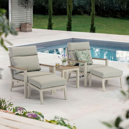 Two mocha coloured reclining chairs with matching footstools and a side table, arranged on a patio beside a swimming pool.