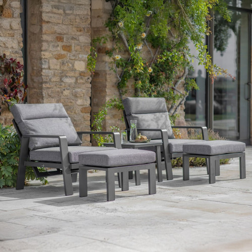 Anthracite two-seat lounge set with two reclining armchairs, matching footstools and a side table on a stone patio.