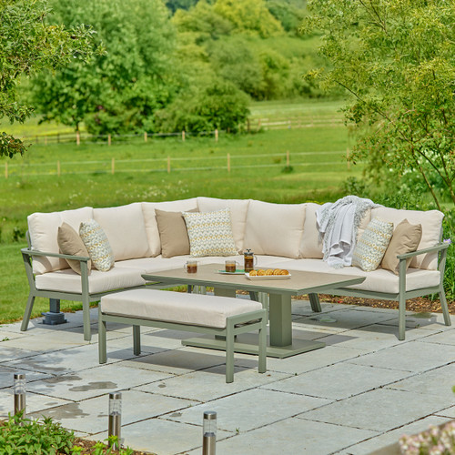 A view of a LG Outdoor Rectangular Modular Corner Garden Furniture set with an adjustable table lowered down on a patio next to a green field