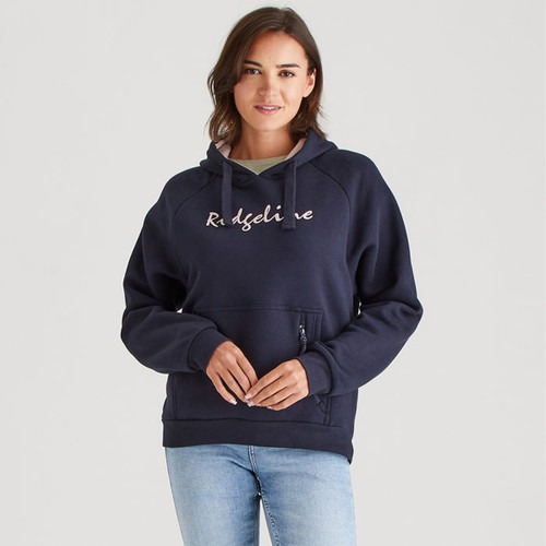Front view of a woman wearing a navy blue pullover hoodie with drawstrings and “Ridgeline” logo text across the chest. The hoodie features a large front kangaroo pocket with a vertical zip detail. She pairs it with light blue jeans against a plain light grey background.
