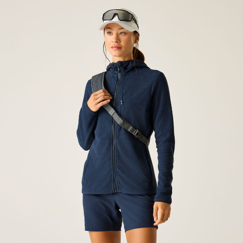 Model wearing a navy textured zip-up hooded jacket with a chest pocket, styled with navy shorts, a cap and sunglasses.