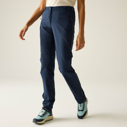 Front view of navy walking trousers on a model, shown with a white top and walking shoes.