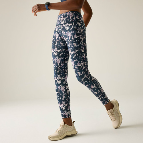 Side view of a model walking in high-waisted navy printed leggings with a wide waistband and ankle-length fit.