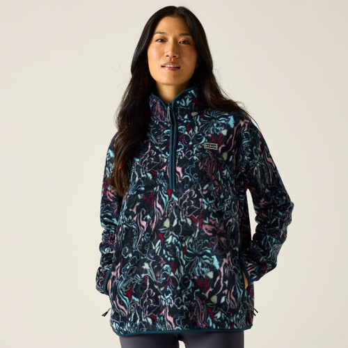 Model wearing a women’s patterned fleece half-zip with high neck, in navy with teal, pink and burgundy print, hands in pockets.