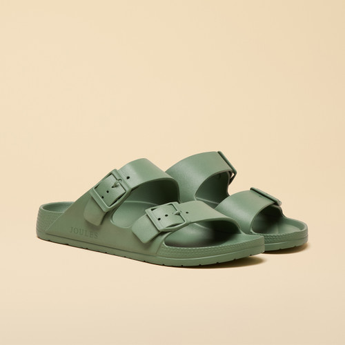 Pair of sage green double-strap sandals with adjustable buckles, shown at a three-quarter angle on a beige background.