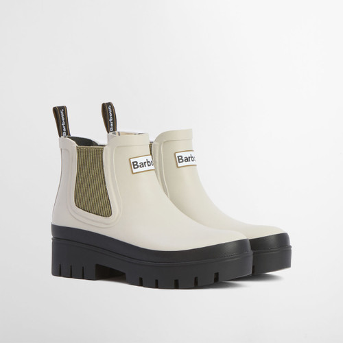 Cream Barbour Chelsea boots with chunky black lug sole and elastic side panels, shown from a three-quarter front angle.