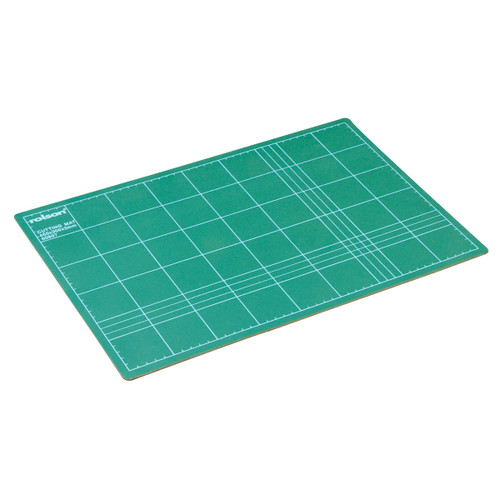 Green cutting mat with white grid lines for measuring. The mat is angled, showcasing its rectangular shape and smooth surface. Ideal for crafting.