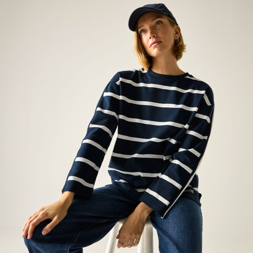 Model wearing a navy long-sleeve top with white horizontal stripes, seated and looking up, studio background.