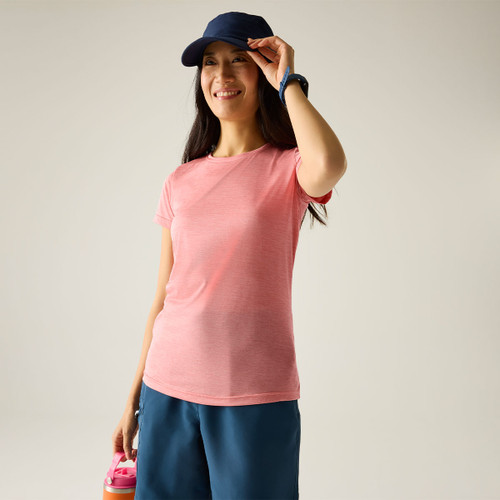 Woman wearing a peach marl short-sleeve T-shirt with a crew neck, styled with a navy cap and blue shorts.