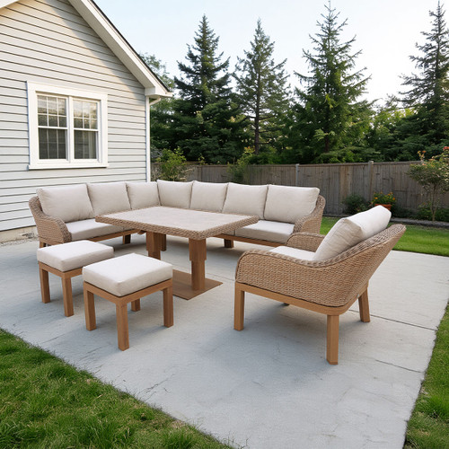 Outdoor patio with beige cushioned wicker furniture set on a concrete slab. Surrounded by grass, trees, and a wooden fence, creating a cosy, serene setting.