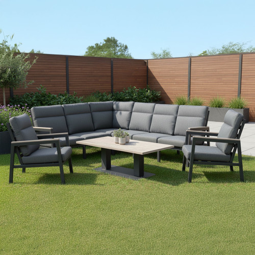 Contemporary outdoor corner lounge set with dark grey cushions, aluminium frames and a wood-effect adjustable table, arranged on a lawn with wooden fencing backdrop.