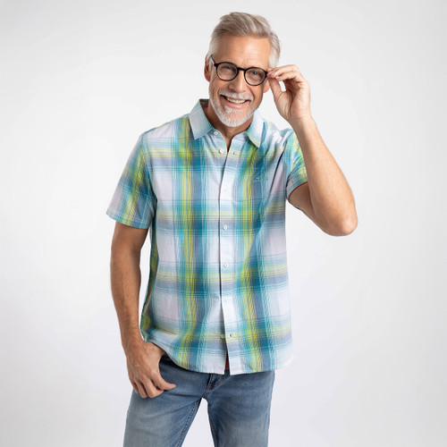 Smiling man wearing a teal, blue and yellow check short-sleeve shirt and jeans, adjusting his glasses.