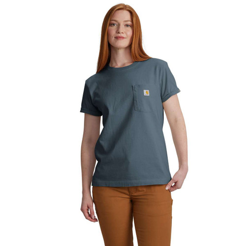Model wearing an iron blue Carhartt pocket T-shirt with a crew neck and chest pocket logo, paired with brown pants.