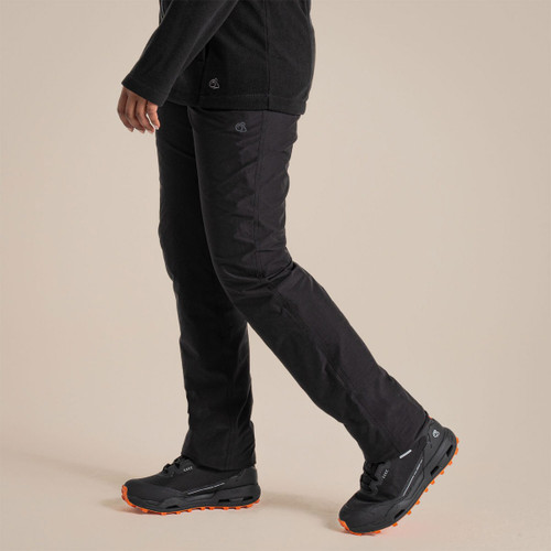 Model wearing black women’s walking trousers with stretch fit, shown in side view while stepping forward.