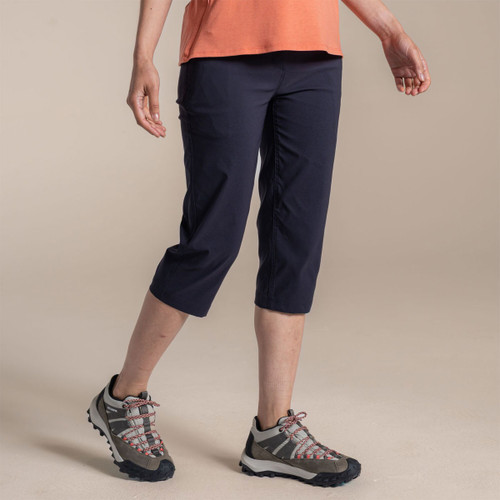 Model wearing navy women’s 3/4 length walking trousers with hiking shoes, side view.