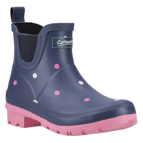 Navy ankle rain boot with pink and white polka dots, a pink sole, and a pull tab. The design conveys a playful and stylish feel.