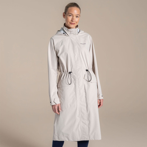 Woman wearing a light grey Craghoppers long waterproof hooded coat with full zip front and adjustable drawcord waist.