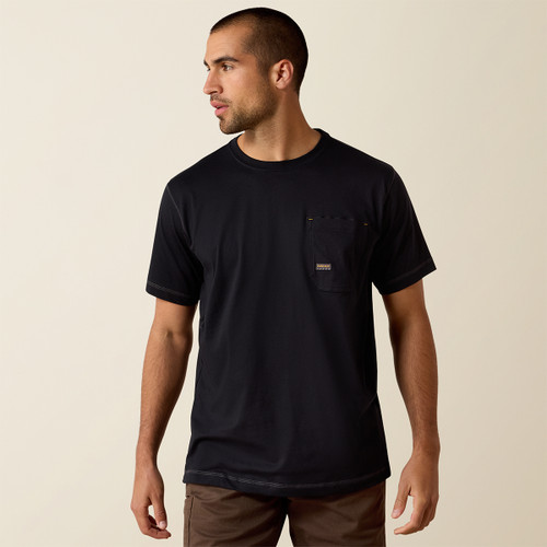 Three-quarter front view of the model wearing the black pocket tee and brown work pants, looking to the side.