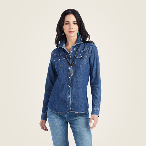 Woman modeling a light blue denim snap-front shirt with chest pockets and western-style yoke details.