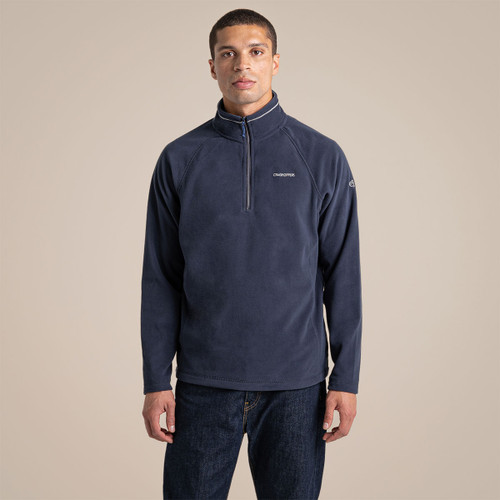 Male model standing in a studio wearing a navy Craghoppers half-zip fleece with jeans, shown from the front.
