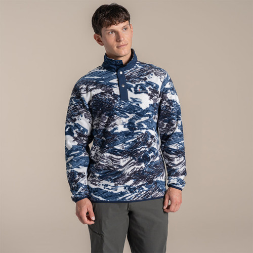Male model standing in a studio wearing a navy and white patterned Craghoppers fleece with a stud half-placket and dark walking trousers.