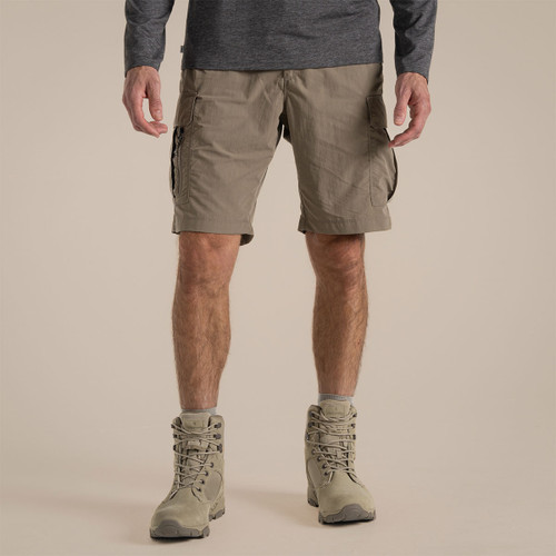 Male model walking in pebble-coloured Craghoppers NosiLife cargo shorts with hiking boots, side view.