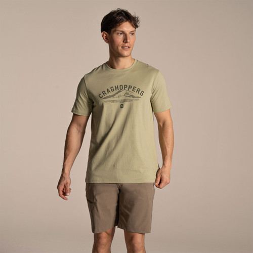 Model wearing bay leaf green Craghoppers short sleeve T-shirt with chest graphic and outdoor shorts.
