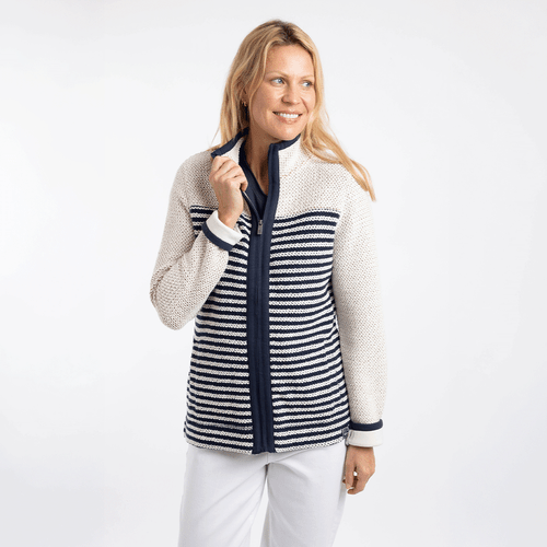 Woman wearing an ecru and navy striped zip-up fleece jacket with textured knit, high collar, and long sleeves, paired with white trousers.