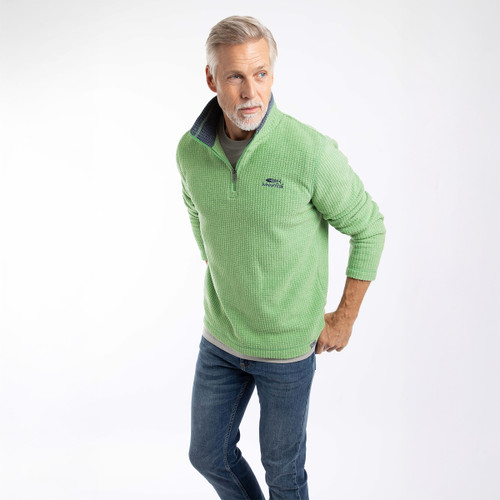 Model wearing a green textured quarter-zip fleece with a stand collar and embroidered chest logo, styled with blue jeans.