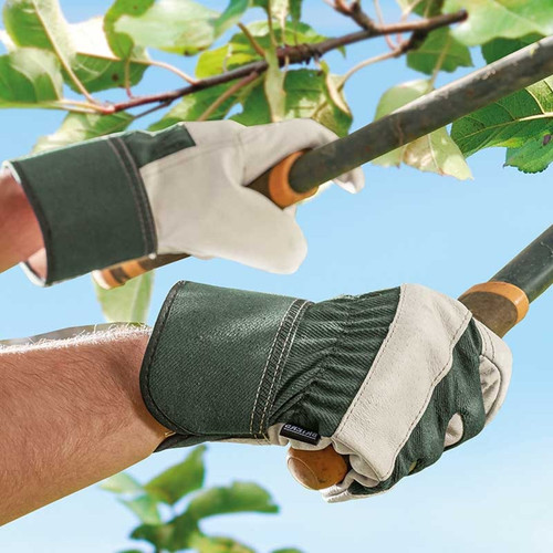 Hands wearing green and white rigger gloves using long-handled loppers to cut tree branches.