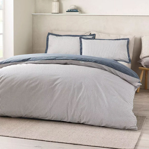 Navy and white pinstripe duvet cover set styled on a double bed in a light, modern bedroom.