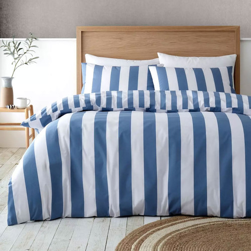 Blue and white striped duvet cover set styled on a bed with wooden headboard in a bright, modern bedroom.