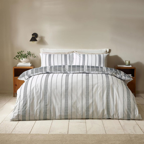 Grey and white striped duvet cover set styled on a double bed in a modern neutral bedroom with wooden bedside tables.