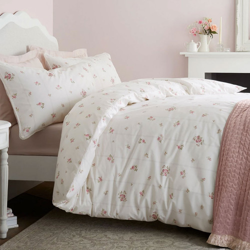 White duvet cover with delicate pink floral print styled on a bed in a soft blush pink bedroom.