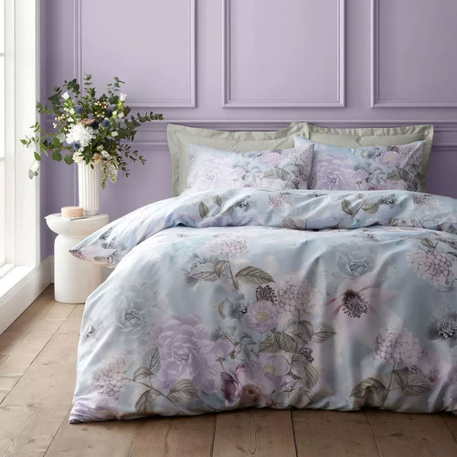 Soft blue floral duvet cover set with large botanical blooms, styled on a double bed in a pastel bedroom.