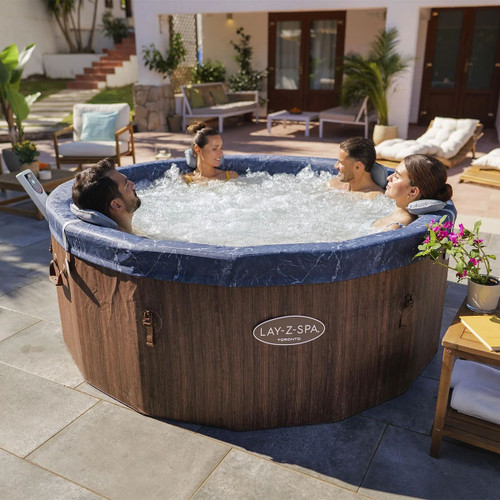 Four adults relaxing in a round Lay-Z-Spa Toronto inflatable hot tub on a sunny patio.