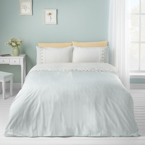 Light blue and white striped duvet cover on a neatly made bed in a pastel bedroom with floral wall art.