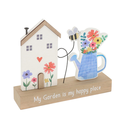 Freestanding wooden table plaque featuring a decorative house with flowers and heart detail, a blue watering can filled with colourful flowers and a small bee, set on a wooden base printed with the words “My Garden is my happy place”.