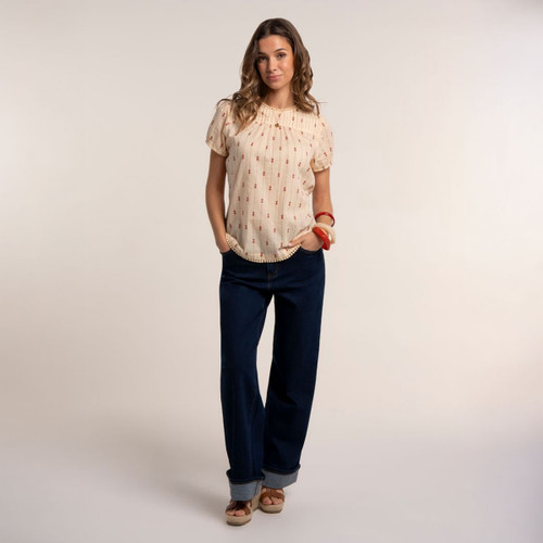 Model wearing a cream short sleeve blouse, paired with dark wide leg jeans and wedge sandals.