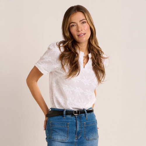 Model wearing a white short sleeve blouse with delicate embroidered detail, styled with a blue denim skirt and black belt.