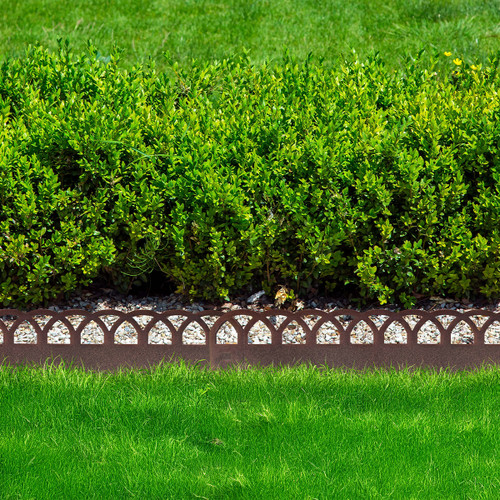 Rust-finish decorative landscape edging with a repeating wave pattern, separating a gravel bed and lawn in front of a trimmed hedge.