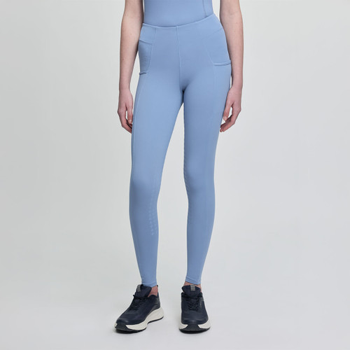 A person wearing light blue, high-waisted leggings and a matching top, with black sneakers. The background is plain light grey.
