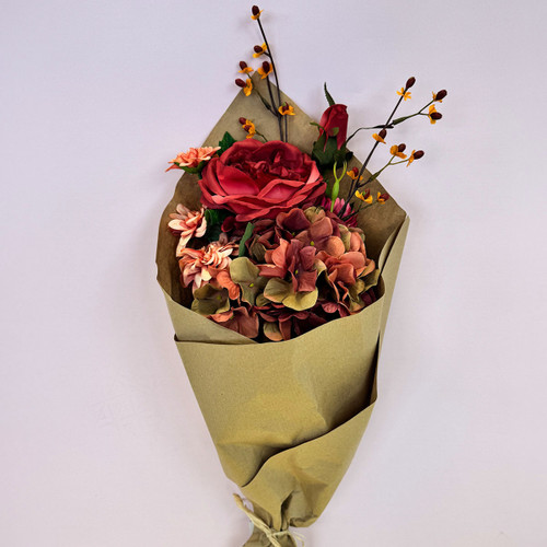 A neatly wrapped bouquet of red and peach flowers with delicate orange sprigs standing upright against a light background.
